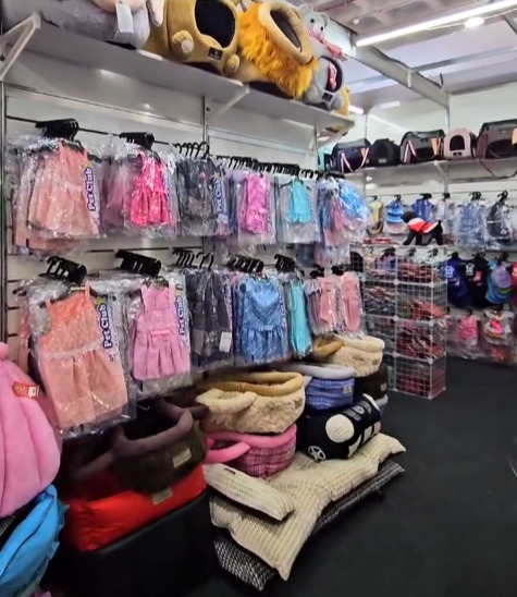 Várias roupas, camas e acessórios para pet em uma exposição da Pet Club.
